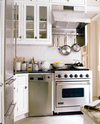 small white kitchen with viking stove and some pots hanging from rack