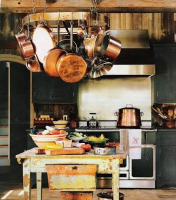 dar green kitchen with copper pots and pans hanging over island