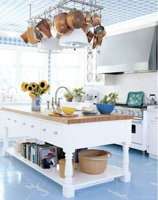 blue and white kitchen with movable island and rack with copper pots