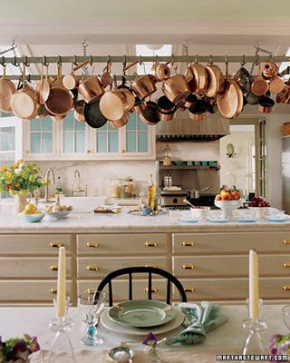 Traditional cream kitchen with marble counter tops and copper pots hanging above the island