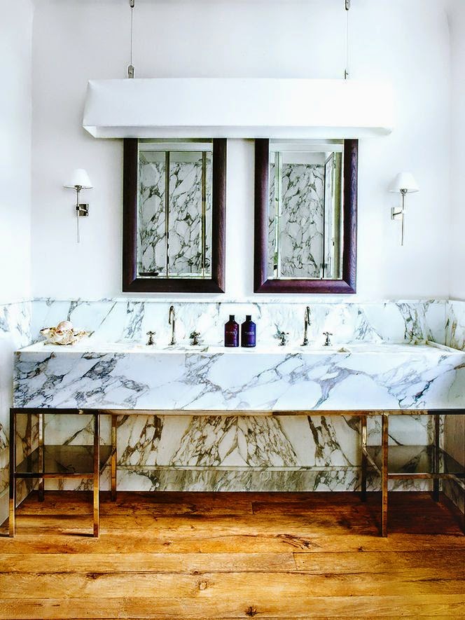 heavily veined marble bathroom with vanitry with chrome legs, wood floor and brown mirrors
