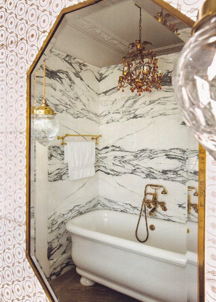 Bathroom walls witn marble, brass towel rack and white freestanding tub