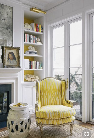 yellow chair and antique mirror above fireplace